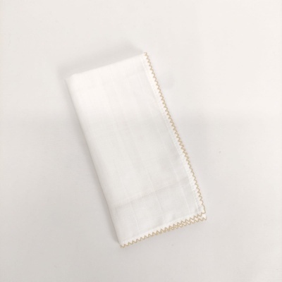 Guardanapo branco de tecido com borda em ponto de ziguezague castanho claro