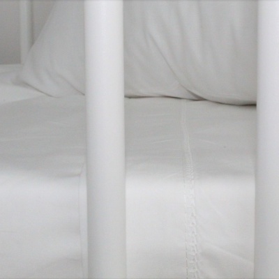 Colchão branco dentro de berço com grades brancas