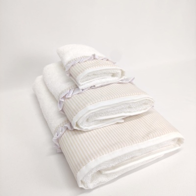 Conjunto de toalhas brancas com faixas bege e laços lilás empilhadas