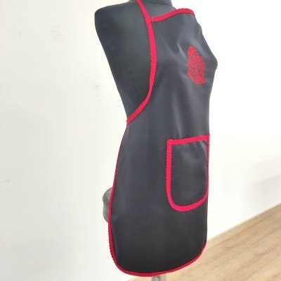 Avental preto com bordas vermelhas e bolso frontal num manequim