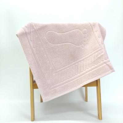 Tapete de banho rosa claro com padrão de pé em relevo pendurado numa estrutura de madeira