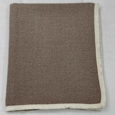 Toalha ou manta castanha clara com bordas brancas dobrada