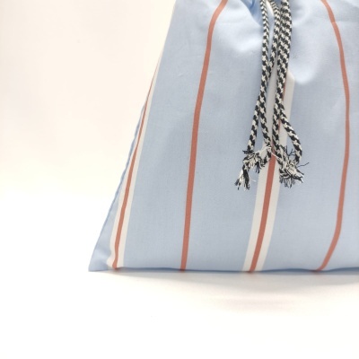 Bolsa de tecido azul com riscas verticais e cordão trançado preto e branco