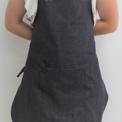 Avental preto com bolso frontal usado por pessoa com camisa branca de mangas curtas