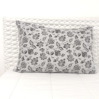 Almofada retangular preta e branca com padrão floral sobre colcha branca acolchoada