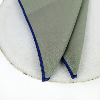 Pano cinza com borda azul sobre superfície branca redonda