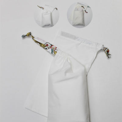 Saco de pano branco com cordão colorido, sobre superfície branca