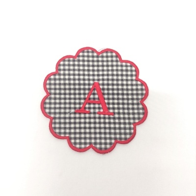 Aplicação de tecido xadrez preto e branco com letra A vermelha.