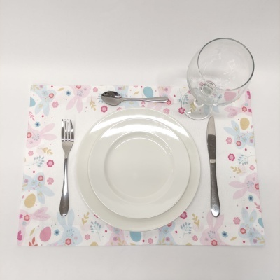 Mesa posta com pratos brancos, talheres em metal, taça de vidro e toalha com padrão floral