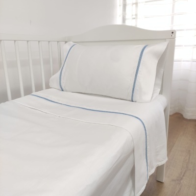 Jogo de cama branco com riscas azuis em cama de madeira branca num quarto iluminado