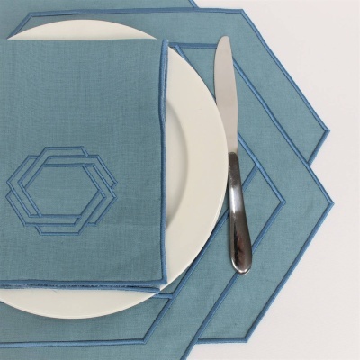 Guardanapo e individual de mesa azuis com padrão geométrico sobre prato branco e faca