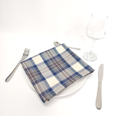 Conjunto de mesa com prato branco, guardanapo xadrez e talheres metálicos