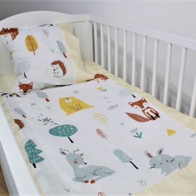 Berço branco com roupa de cama estampada com desenhos de animais coloridos