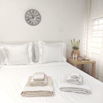 Quarto com cama feita, toalhas empilhadas e decoração minimalista branca e bege