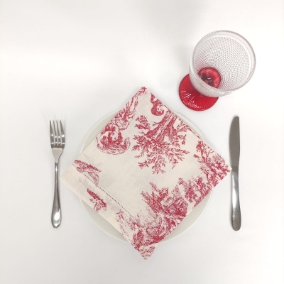 Conjunto de jantar com guardanapo decorativo vermelho e branco, talheres metálicos e copo com pé vermelho