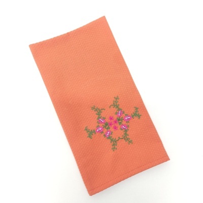 Guardanapo de tecido laranja com bordado floral rosa e verde