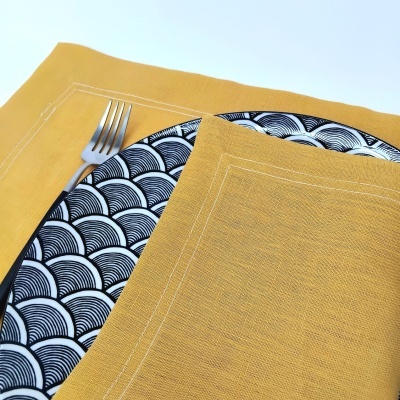 Conjunto de loiça preto e branco com guardanapo e toalha amarelos e garfo.