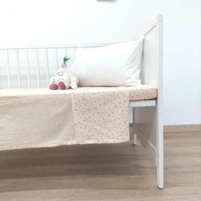 Berço branco com roupa de cama rosa e branca e boneco pelúcia