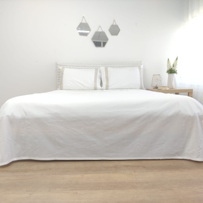 Cama de casal branca com decoração minimalista numa sala clara