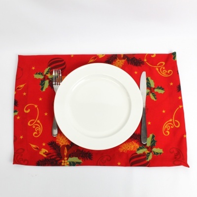 Toalhete natalício vermelho com prato branco, garfo e faca sobre fundo branco