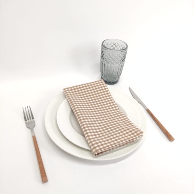 Conjunto de pratos brancos, guardanapo bege às peças, talheres com cabo de madeira e copo cinzento texturizado