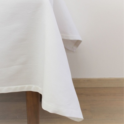 Toalha de mesa branca com padrão fino numa mesa de madeira