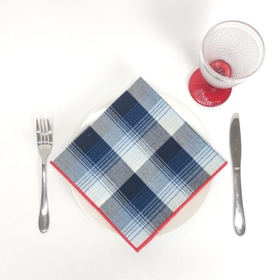 Guardanapo xadrez azul com prato, talheres e copo com base vermelha