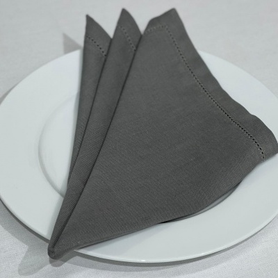 Guardanapo cinzento dobrado em prato branco sobre toalha branca