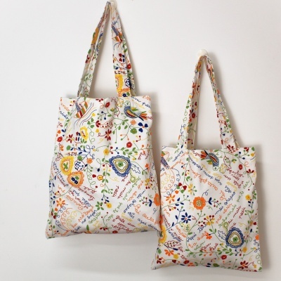 Duas malas de tecido com padrão floral colorido e texto manuscrito penduradas na parede