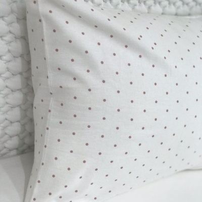 Travesseiro branco com pontos cor-de-rosa sobre superfície acolchoada branca