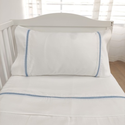 roupa de cama branca com detalhes azuis num berço branco