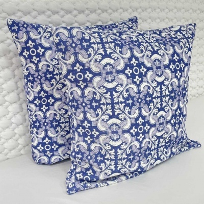 Duas almofadas quadradas com padrão azul e branco com motivos florais e geométricos