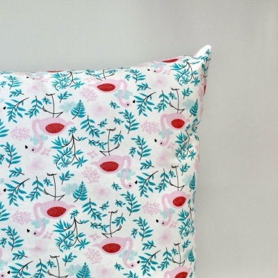 Almofada com padrão colorido de flamingos e folhas sobre fundo branco