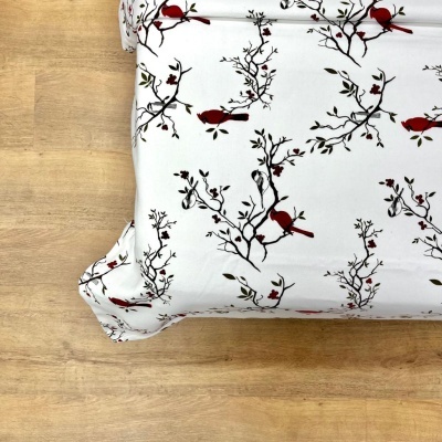 Lençol branco com pássaros vermelhos e árvores pretas sobre colchão