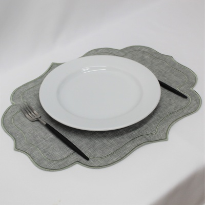 Prato branco sobre individual cinzento ondulado com talheres pretos