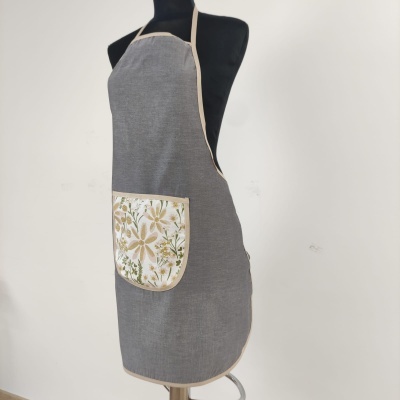Avental cinzento com bolso floral e bordas bege em manequim preto