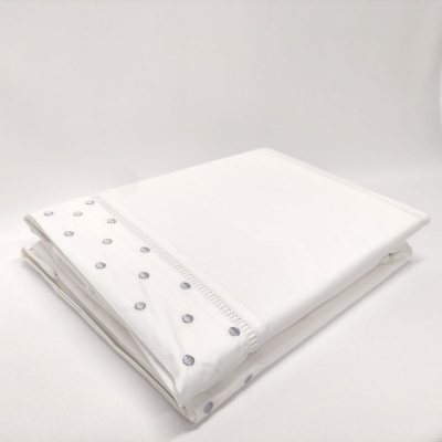 Lençol branco com bordado de bolinhas azuis dobrado