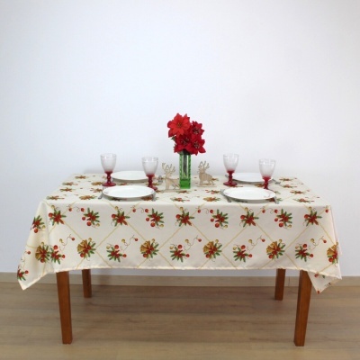 Mesa com toalha natalícia, pratos, copos e vaso com flores vermelhas