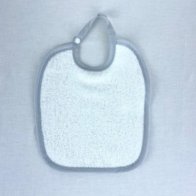 Babete branco com bordas e presilha cinza sobre fundo cinza