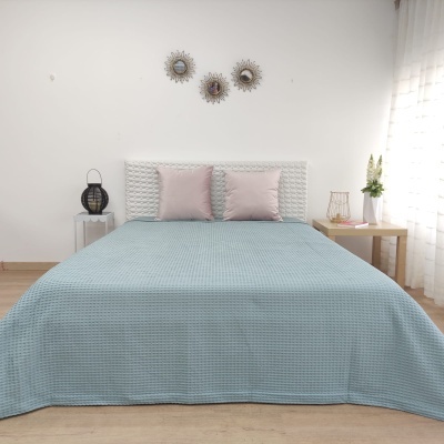 Quarto com cama de cabeceira branca almofadada e colcha azul clara