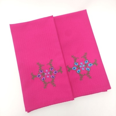 Dois panos de tecido rosa com bordados florais coloridos sobre fundo branco