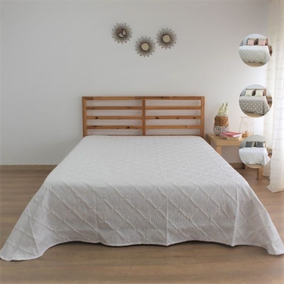 Colcha bege clara acolchoada em cama de madeira com decoração minimalista