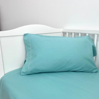 Fronha e lençol azuis num berço branco