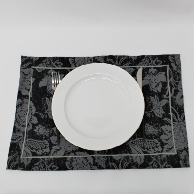 Jogo americano preto e cinza com prato branco, garfo e faca