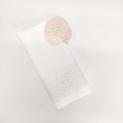 Toalha branca com faixa de renda e concha natural sobre fundo branco