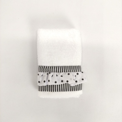 Toalha branca com bainha riscada e detalhe de bolinhas pretas.
