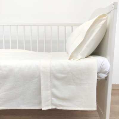 Cama de criança branca com roupa de cama branca creme