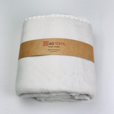 Manta branca felpuda com etiqueta castanha da AG Têxtil.