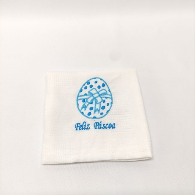Toalha branca bordada com ovo de Páscoa azul e texto Feliz Páscoa