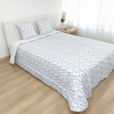 Colcha e almofadas florais em cama branca numa sala iluminada